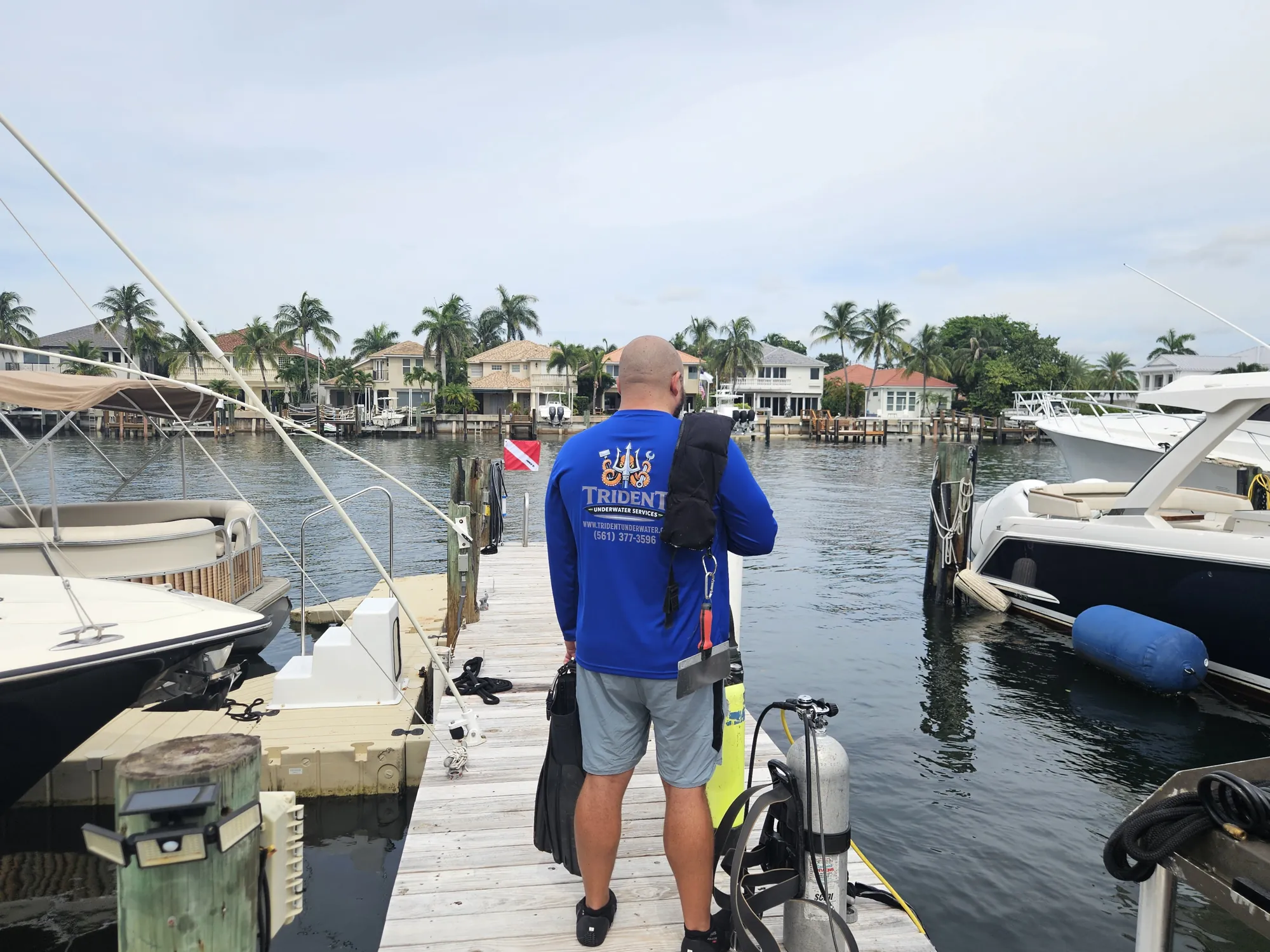 Trident diver carrying fins and gear down the dock