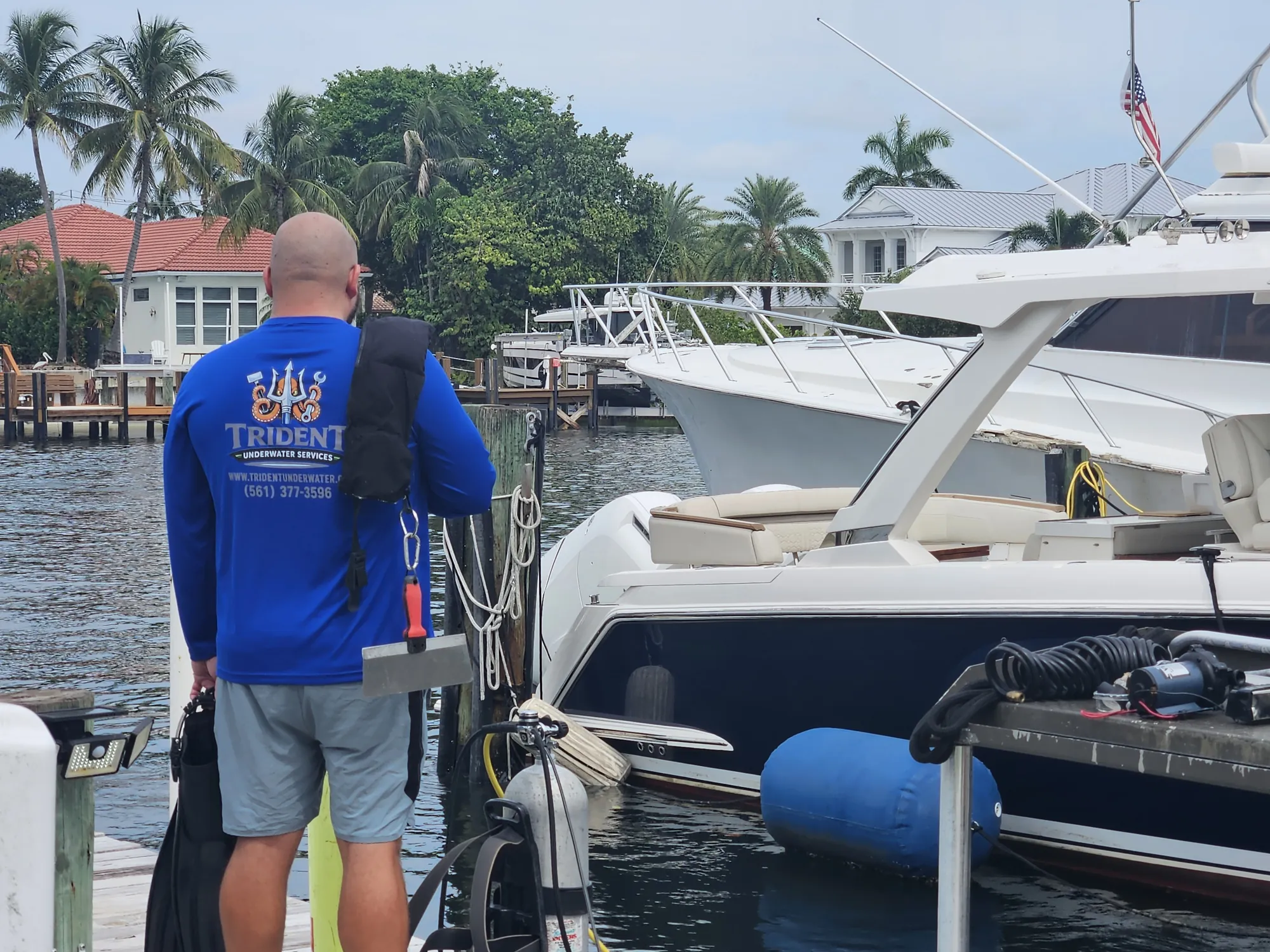 Trident Underwater diver preparing gear beside a yacht at the dock